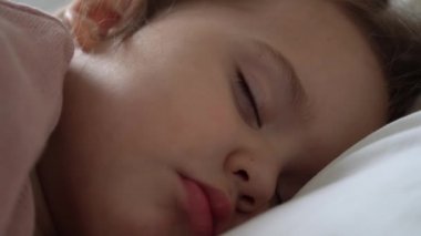 Otantik, şirin, tatlı, rahat, beyaz ve gri yatakta tatlı tatlı uyuyan küçük kız. Güzel, yorgun çocuk, dinlenme zamanı, dinlenme zamanı. Beşikteki çocuk. Bakım, Çocukluk, Ebeveynlik, Yaşam Konsepti
