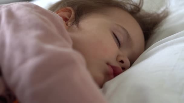 Authentiek schattig meisje slapen zoet in comfortabele witte en grijze bed close-up. Mooi vermoeid kind hebben rusttijd zachtjes kalmerend. Een kind in de wieg. Zorg, Jeugd, Ouderschap, Leven concept — Stockvideo
