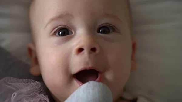 Крупный план Happy playful kid 6 month old. Новорожденный мальчик смотрит в камеру после душа на белой мягкой кровати. ребенок просыпается перед сном с игрушкой. Детство, материнство, семья, детская концепция — стоковое фото
