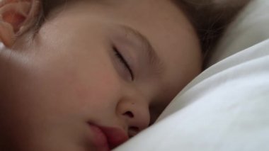 Otantik, şirin, tatlı, rahat, beyaz ve gri yatakta tatlı tatlı uyuyan küçük kız. Güzel, yorgun çocuk, dinlenme zamanı, dinlenme zamanı. Beşikteki çocuk. Bakım, Çocukluk, Ebeveynlik, Yaşam Konsepti