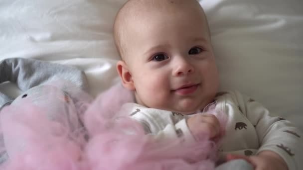 Close-up Vrolijk speels kind van 6 maanden oud. Pasgeboren jongen kijkt naar camera na bad douche op wit zacht bed. baby kind wakker tijd voor het slapen gaan met Toy. Jeugd, moederschap, familie, kinderconcept — Stockvideo