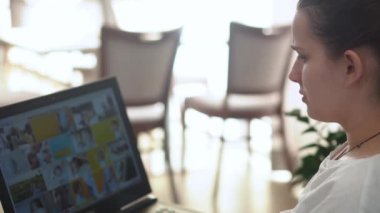 Oturma odasında dizüstü bilgisayarda sohbet eden otantik genç kadın. Masada aratarak yazma. Bilgisayar taraması yapan mutlu bayan. Buisenes, Eğitim, Teknoloji Konsepti