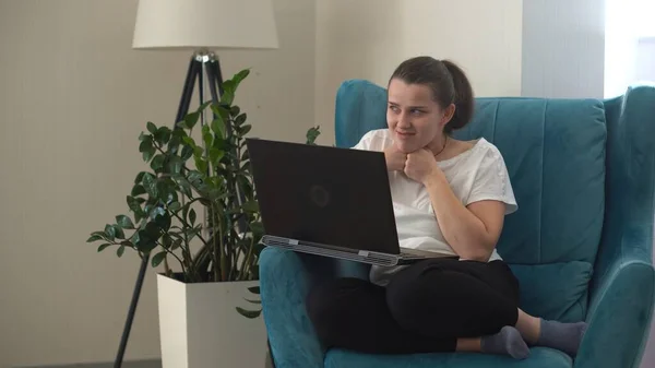 Autentyczna, zestresowana kobieta pracująca na czacie w salonie na laptopie. Pisanie wyszukiwania za pomocą IT. Zmęczona smutna pani pracująca na komputerowym internecie na wygodnym krześle. Buisenes, Edukacja, Koncepcja technologii — Zdjęcie stockowe