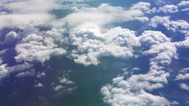 Vista desde la ventana del avión hasta el ala. Hace buen tiempo afuera. Nubes en el cielo. Vista desde el ojo de buey del avión hasta el suelo. Volando sobre las nubes en lo alto del cielo. El pasajero mira hacia fuera — Vídeos de Stock