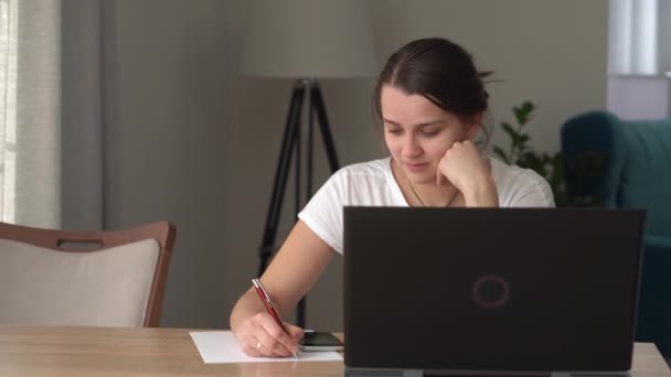 Hiteles kaukázusi fiatal nő beszél a laptopon otthon, a nappaliban. Írás Keresés használata az asztalnál. Boldog hölgy dolgozik a számítógép böngészés internet. Buisenes, Oktatás, Technológia koncepció — Stock videók
