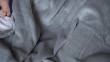 Otantik, şirin, tatlı, rahat beyaz ve gri yatakta uyuyan bir kız. Güzel, yorgun çocuk, dinlenme zamanı, dinlenme zamanı. Beşikteki çocuk. Bakım, Çocukluk, Ebeveynlik, Yaşam Konsepti