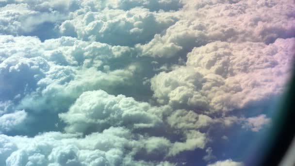 View from the airplane window to the wing. Good weather outside. Clouds in the sky. View from the porthole of the plane to the ground. Flying above the clouds high in the sky. The passenger looks out — Stock Video