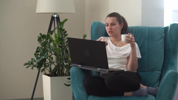 Authentische junge Frau plaudert auf Laptop im Wohnzimmer. Schreiben Suchen mit Hilfe von IT. Happy Lady Arbeiten am Computer Surfen im Internet auf Comfortale Easy Chair. Buisenes, Bildung, Technologiekonzept — Stockvideo