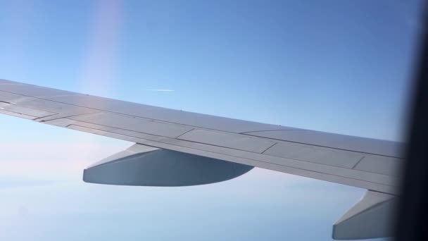 Vue de la fenêtre de l'avion à l'aile. Il fait beau dehors. Nuages dans le ciel. Vue depuis le hublot de l'avion jusqu'au sol. Voler au-dessus des nuages haut dans le ciel. Le passager regarde dehors — Video
