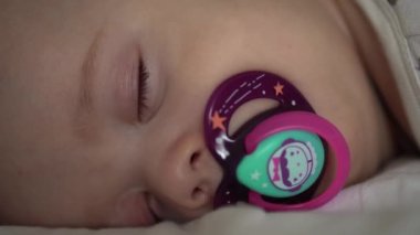 bebeklik, çocukluk, gelişim, tıp ve sağlık konsepti - yeni doğmuş tombul, uyuyan bebeğin yakın çekimi 6 ay karın üstü yatarak beyaz arka planda battaniye ile kaplanmış bir emzik.
