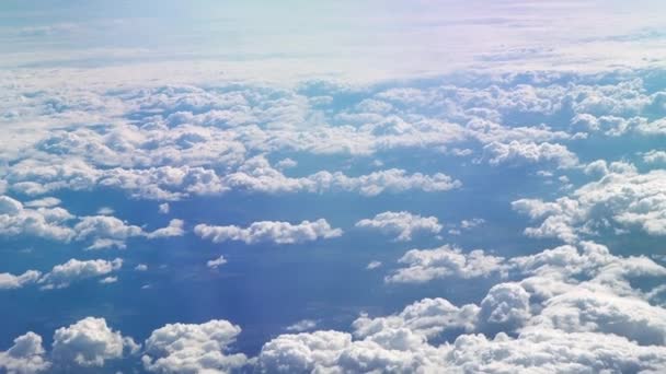 Kilátás a repülőgép ablakából a szárnyra. Jó idő van odakint. Felhők az égen. Kilátás a hajóablakból a földre. Repül a felhők felett magasan az égen. Az utas vigyáz. — Stock videók