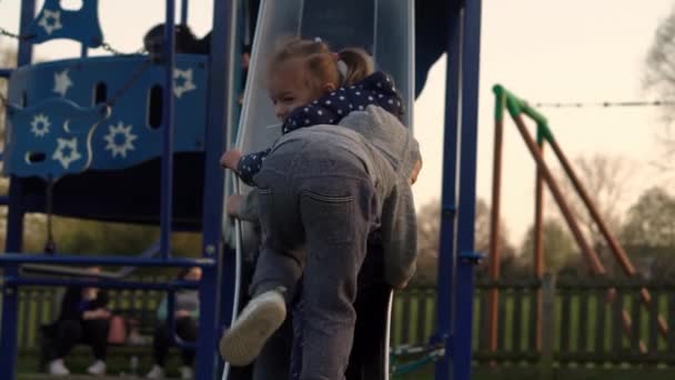 Três crianças felizes se divertindo deslizando. Sorrindo Irmãos engraçados amigos brincando lá fora. crianças emocionais passeios no carrossel no jardim infantil no parque. Família feliz, infância, Amizade — Vídeo de Stock