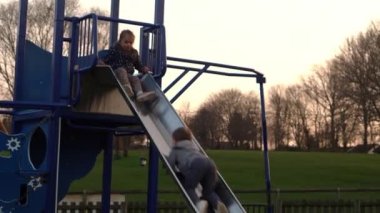 Üç küçük mutlu çocuk kayarak eğleniyor. Gülen Komik Kardeşler 'in arkadaşları dışarıda oynuyor. Duygusal çocuklar parktaki çocuk parkında atlı karıncaya biniyorlar. Mutlu aile, çocukluk, arkadaşlık.