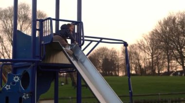 Üç küçük mutlu çocuk kayarak eğleniyor. Gülen Komik Kardeşler 'in arkadaşları dışarıda oynuyor. Duygusal çocuklar parktaki çocuk parkında atlı karıncaya biniyorlar. Mutlu aile, çocukluk, arkadaşlık.