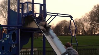 Üç küçük mutlu çocuk kayarak eğleniyor. Gülen Komik Kardeşler 'in arkadaşları dışarıda oynuyor. Duygusal çocuklar parktaki çocuk parkında atlı karıncaya biniyorlar. Mutlu aile, çocukluk, arkadaşlık.