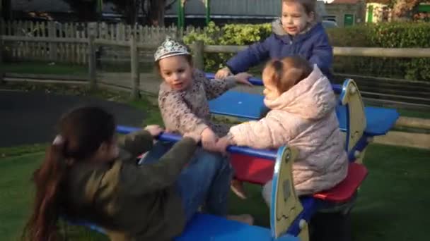 Little Happy Group Children Different Ege haben Spaß beim Karussell drehen. Lächelnde Geschwister Freunde spielen draußen. Emotionale Kinder fahren auf Karussell auf Spielplatz im Park.Glückliche Familie, Kindheit — Stockvideo