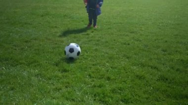 Mutlu çocuk ailesi bahar parkında eğleniyor. Küçük Çocuk Koş. Çocuk Çocuk Yeşil Çimende Siyah Beyaz Klasik Futbol Topu Sürüyor. İnsanlar futbol oynuyor. Çocukluk, Spor, Şampiyonluk Konsepti
