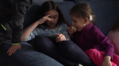 Otantik 3 küçük anaokulu çocuğu reşit olmayan çocuk kardeşler çizgi film izleyip akıllı telefon aygıtı bilgisayarında sohbet ediyorlar. Aile, çocukluk, arkadaşlık