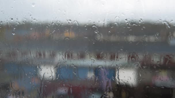 Gotas de lluvia en el cristal de la ventana en la temporada de monzones. Gotas de agua fluyen por el fondo borroso de la naturaleza, tiro estático. El clima exterior es malo. Otoño o primavera aguaceros del día lluvioso. Depresión, concepto de melancolía — Vídeo de stock
