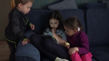 Otantik 3 küçük anaokulu çocuğu reşit olmayan çocuk kardeşler çizgi film izleyip akıllı telefon aygıtı bilgisayarında sohbet ediyorlar. Aile, çocukluk, arkadaşlık
