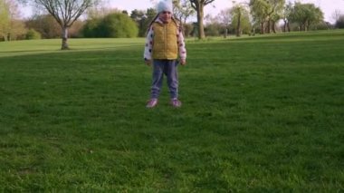 Mutlu çocuk ailesi bahar parkında eğleniyor. Küçük Çocuk Koş. Çocuk Kız Yeşil Çimen Üzerinde Siyah Beyaz Klasik Futbol Topu Sürüyor. İnsanlar futbol oynuyor. Çocukluk, Spor, Şampiyonluk Konsepti