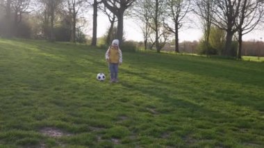 Mutlu çocuk ailesi bahar parkında eğleniyor. Küçük Çocuk Koş. Çocuk Kız Siyah Beyaz Beyazın Üzerinde Dans Ediyor Klasik Futbol Topu Yeşil Çimen Üzerinde. İnsanlar futbol oynuyor. Çocukluk, Spor, Şampiyonluk Konsepti