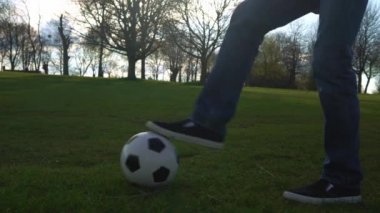 Mavi Kot Giyen ve Mokasen Giyen Adam Siyah ve Beyaz Klasik Futbol Topuyla hokkabazlık yapıyor. İnsanlar spor için içeri giriyor. Genç çocuk futbol oynuyor. Mutlu Aile Ekibi parkta vakit geçirdi. Sağlıklı Yaşam, Şampiyonluk