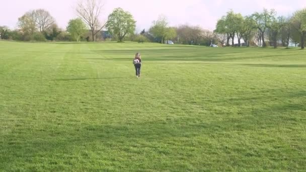 Buona famiglia di bambini che si divertono nel parco primaverile. Little Kid Run. Bambino ragazzo dribbles nero bianco classico calcio palla su erba verde. Persone che giocano a calcio. Infanzia, Sport, Championship Concept — Video Stock