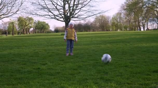 春の公園で楽しい子供たちの幸せな家族。リトル・キッド・ラン。子供の女の子は緑の草の上にブラックホワイトクラシックサッカーボールをドリブル。サッカーをしている。子供時代,スポーツ,選手権のコンセプト — ストック動画