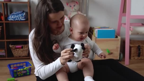 Amore tenero caucasico giovane mamma holding adorabile carino bambino ragazzo figlio abbracciare baciare piccolo bambino. felice affettuoso lungo dai capelli madre cura coccole con infantile bambina figlia giocare a casa. — Video Stock