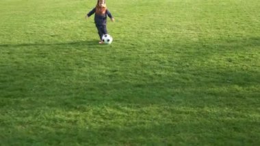 Mutlu çocuk ailesi bahar parkında eğleniyor. Küçük Çocuk Koş. Çocuk Çocuk Yeşil Çimende Siyah Beyaz Klasik Futbol Topu Sürüyor. İnsanlar futbol oynuyor. Çocukluk, Spor, Şampiyonluk Konsepti