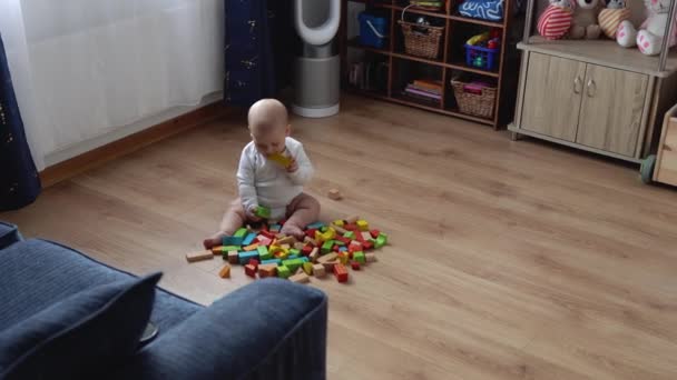 Glückliches Neugeborenes im Spielzimmer. Kleinkinder spielen zu Hause mit Holzspielzeug und bauen Konstruktionen aus geometrischen Figuren. Kinder verbringen Zeit während des Motorikspiels. Kindheit, Elternschaft — Stockvideo