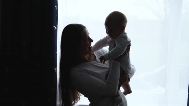 Silhouette Loving Tender Caucasian Young Mum Holding Adorable Cute Baby Boy Son Embracing Kissing Small Kid. Happy Affectionate Long Haired Mother Cuddling With Infant Child Girl Daughter At Home. — ストック動画