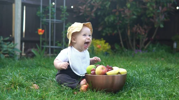 Happy Baby zit met voetbal zwart wit klassieke bal op groen gras. Schattige baby die buiten speelt in de tuin. Kleine kinderen met ouders. Voetbal, kampioenschap, sportconcept — Stockfoto