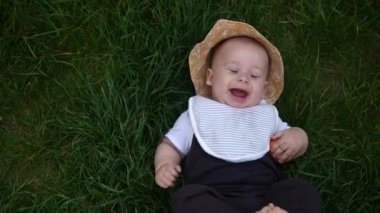 Yaz panama şapkalı küçük mutlu bebek yaz güneşli bir günde çimenlere çıplak ayakla düşüyor. Bebek Çocuk Bebek Çocuk Gülümseyen Yüz Bahçedeki Aile Doğası 'nın dışındaki kameraya bak.
