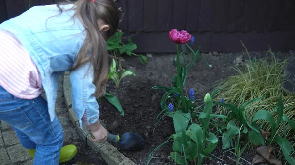 子供を持つ母親主婦息子娘は、母親が庭の世話をするのを助ける花を植えるために土を準備する手袋を着用しています。環境を植える庭師の支援｜家族の自然 — ストック写真
