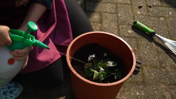Счастливая дочка девочка дочка носить работает перчатки гуминовые сапоги посадки цветов в горшок в саду. Ребенок помогает матери на улице. Семейное озеленение, экологическая весна — стоковое фото