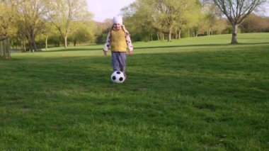 Mutlu çocuk ailesi bahar parkında eğleniyor. Küçük Çocuk Koş. Çocuk Kız Yeşil Çimen Üzerinde Siyah Beyaz Klasik Futbol Topu Sürüyor. İnsanlar futbol oynuyor. Çocukluk, Spor, Şampiyonluk Konsepti