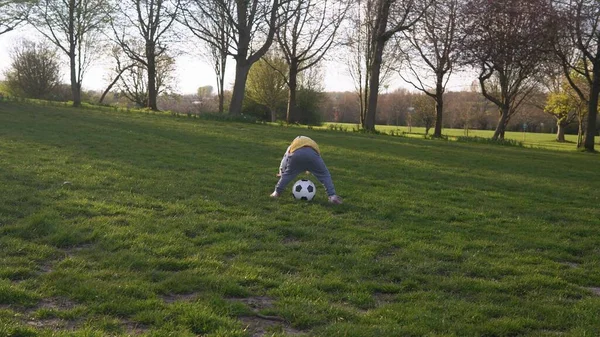 春の公園で楽しい子供たちの幸せな家族。リトル・キッド・ラン。子供の女の子は緑の草の上にブラックホワイトクラシックサッカーボールをドリブル。サッカーをしている。子供時代,スポーツ,選手権のコンセプト — ストック写真