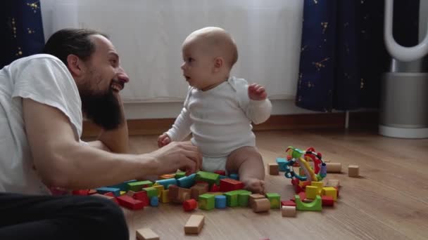 Happy Baby In Playing Room With Dad. Infant Kid Play With Wooden Toys At Home Build Constructions From Geometric Figures. Child Have Spend Time During Motor Skills Game. Childhood, Parenthood Concept — стоковое видео