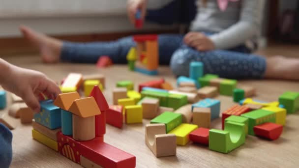 Dos hermanos preescolares felices Niños Niña en la sala de juegos. Los niños de la misma edad juegan con juguetes de madera en la construcción casera. El bebé ha pasado tiempo en casa. Infancia, paternidad, concepto de amistad — Vídeo de stock