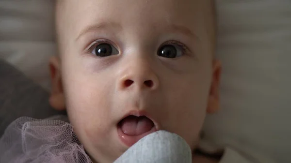 Крупный план Happy playful kid 6 month old. Новорожденный мальчик смотрит в камеру после душа на белой мягкой кровати. ребенок просыпается перед сном с игрушкой. Детство, материнство, семья, детская концепция — стоковое фото