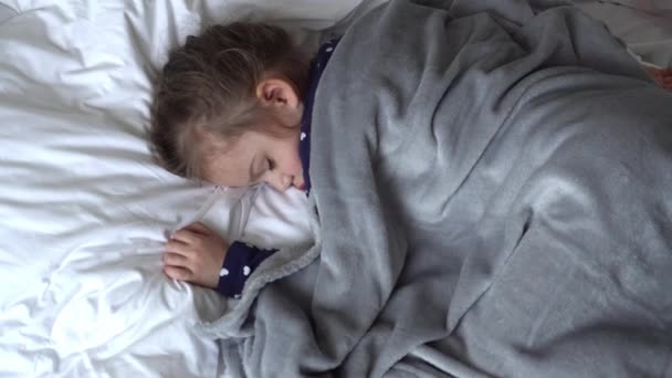 Autentické roztomilé holčička spí sladce v pohodlné bílé a šedé postele střední plán. Krásné unavené dítě si odpočinout Jemně uklidňující. Dítě v Krabici. Péče, Dětství, Rodičovství, Životní koncept — Stock video