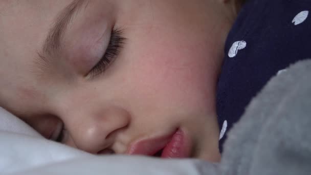 Autêntico bonito menina dormindo docemente em confortável branco e cinza cama close up. Linda criança cansada ter tempo de descanso suavemente calmante. Miúdo no berço. Cuidados, Infância, Paternidade, Conceito de vida — Vídeo de Stock