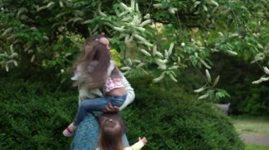 İki kız çocuğu olan mutlu bir aile annesi. Ağaçlarda çiçek koklayarak, bahçe parkında tatilin tadını çıkararak eğleniyor. Gülümseyen çocuklar gün batımını birlikte geçiriyorlar. Anneler Günü.