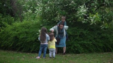 Mutlu aile annesi, koşuşturmaca oynayan üç küçük kardeş anne kucaklaşması yaz tatilinin tadını bahçede ya da parkta çıkarıyor. Gülümseyen ebeveynler çocuklar akşam günbatımında birlikte vakit geçiriyorlar.