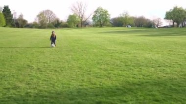 Mutlu çocuk ailesi bahar parkında eğleniyor. Küçük Çocuk Koş. Çocuk Çocuk Yeşil Çimende Siyah Beyaz Klasik Futbol Topu Sürüyor. İnsanlar futbol oynuyor. Çocukluk, Spor, Şampiyonluk Konsepti