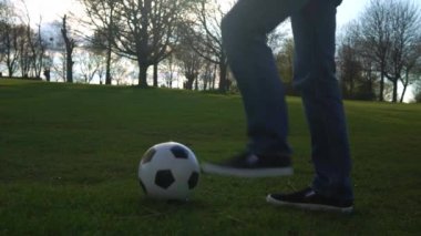 Mavi Kot Giyen ve Mokasen Giyen Adam Siyah ve Beyaz Klasik Futbol Topuyla hokkabazlık yapıyor. İnsanlar spor için içeri giriyor. Genç çocuk futbol oynuyor. Mutlu Aile Ekibi parkta vakit geçirdi. Sağlıklı Yaşam, Şampiyonluk