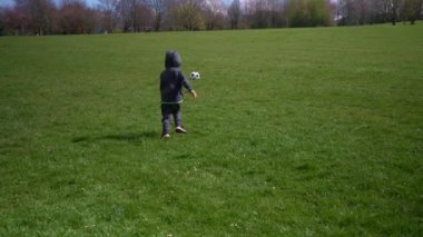 Mutlu çocuk ailesi bahar parkında eğleniyor. Küçük Çocuk Koş. Çocuk Çocuk Yeşil Çimende Siyah Beyaz Klasik Futbol Topu Sürüyor. İnsanlar futbol oynuyor. Çocukluk, Spor, Şampiyonluk Konsepti