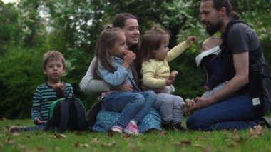 Mutlu aile annesi baba üç küçük kardeş çocuklar bahçe parkında yaz tatilinin tadını çıkarırken eğleniyor. Gülümseyen ebeveynler çocuklar akşam günbatımında birlikte vakit geçiriyorlar.